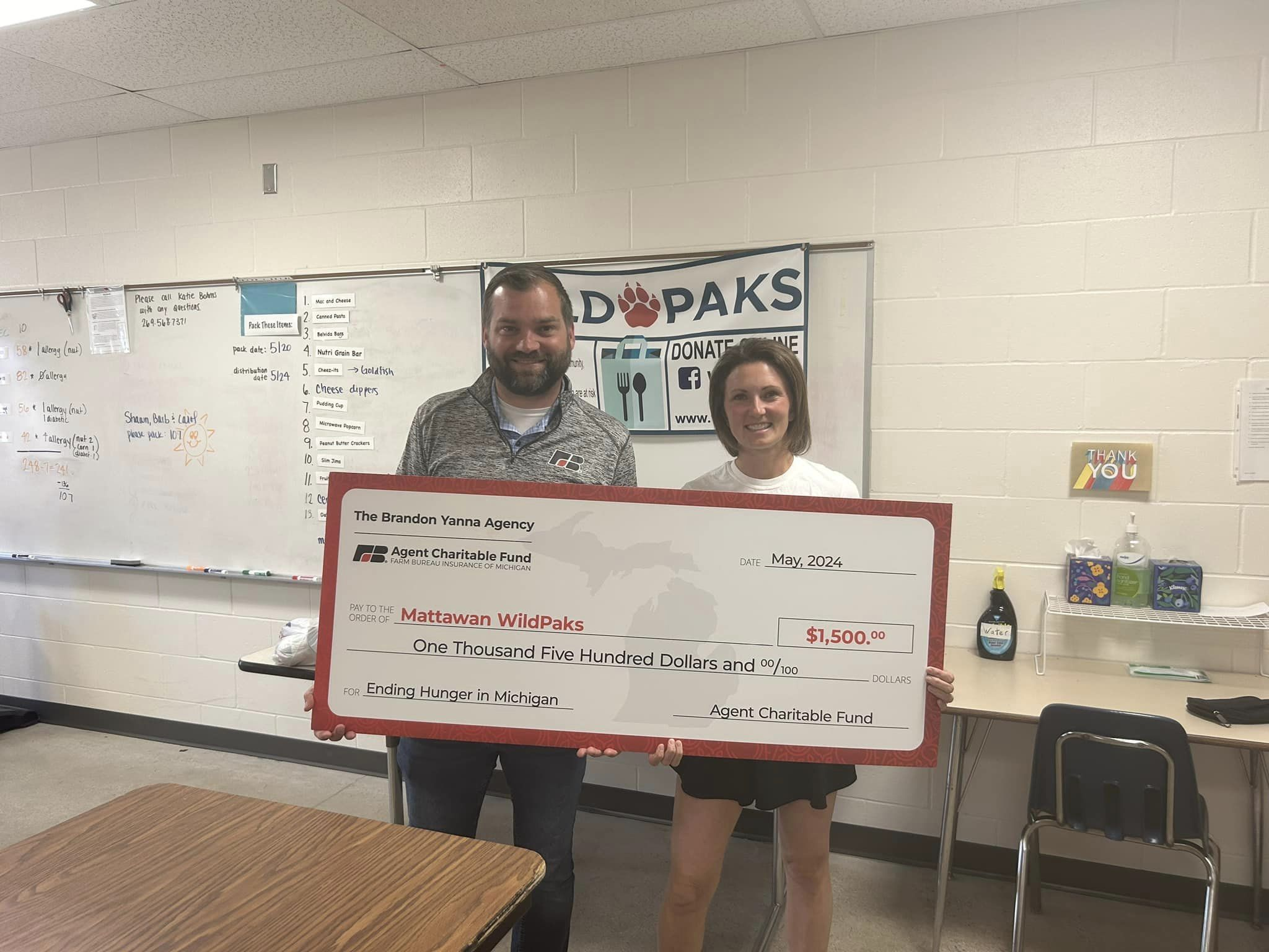 Brandon Yanna presenting $1,500 charitable donation to Mattawan WildPaks